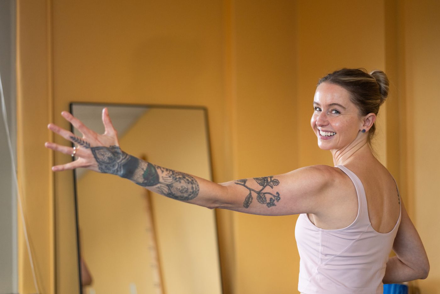 Caroline smiling over her shoulder, arm raised, in her movement studio