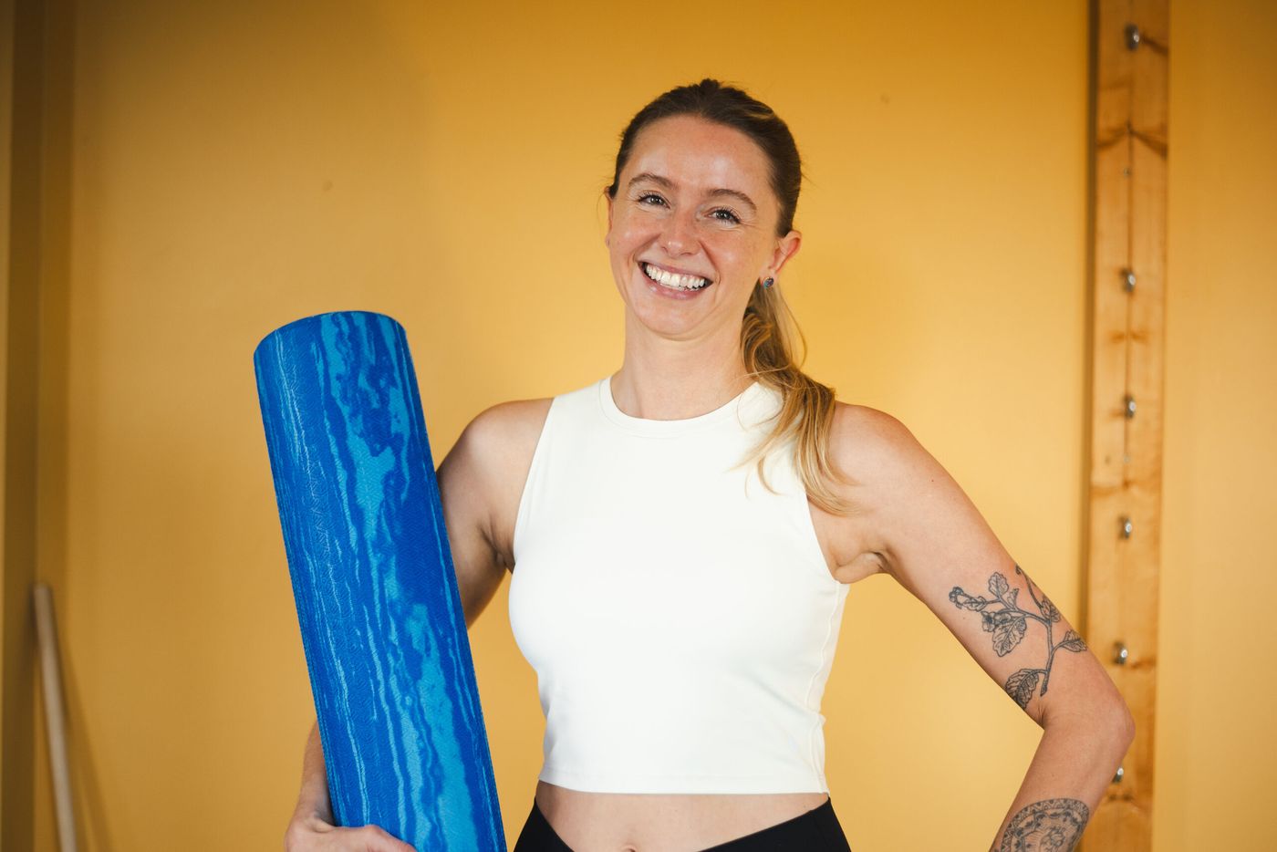 Caroline smiling, holding a foam roller