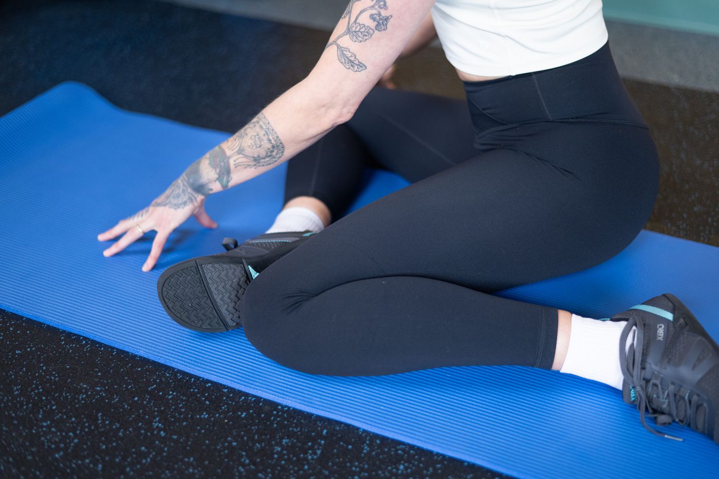 Caroline seated on a mat in a hip mobility stretch
